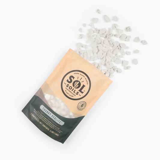 a tan bag of sol soils chunky perlite laying down with its white rock like contents spilled onto the white background