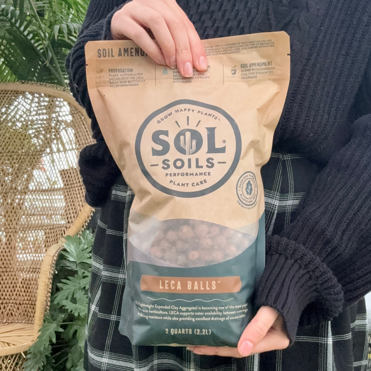 a person holding a bag labeled sol soils lena balls with plants in the background