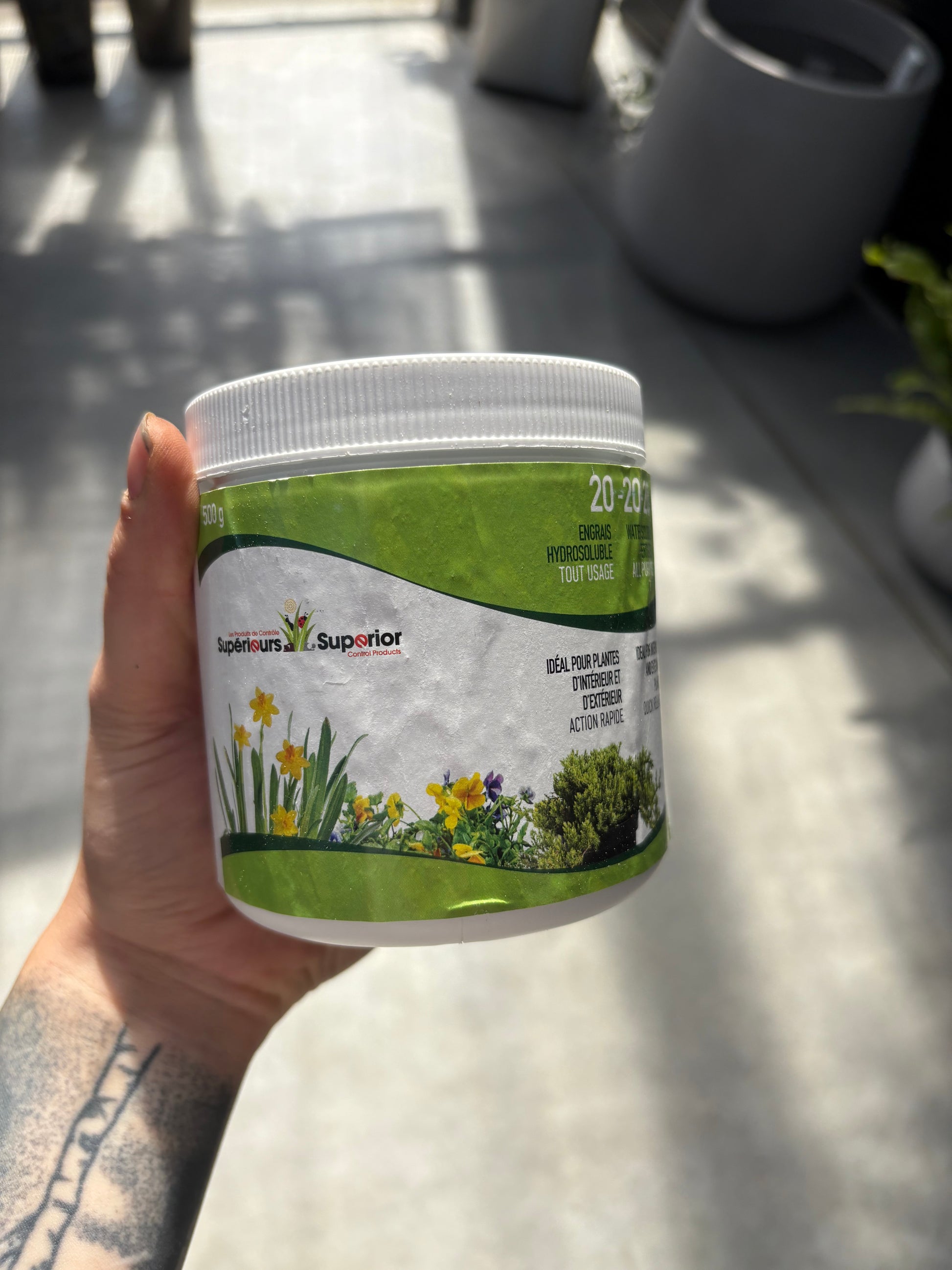 Hand holding a container with a green label on a light surface