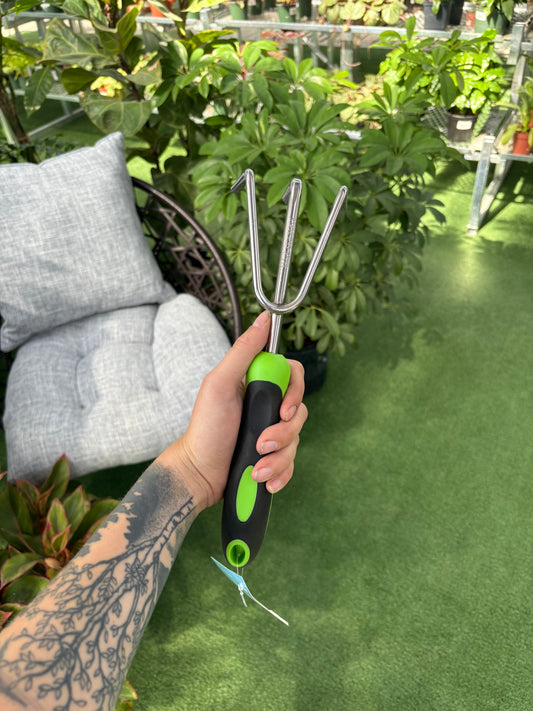 Person holding a garden tool with plants in the background