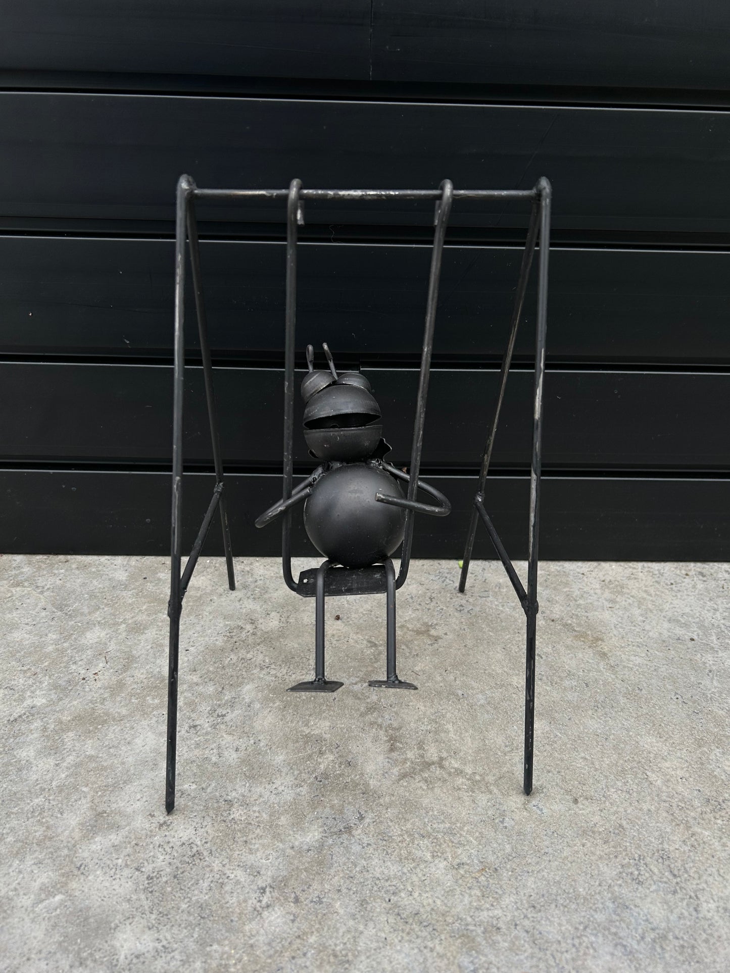 a black metal bug on a black metal swing
