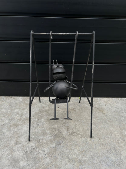 a black metal bug on a black metal swing