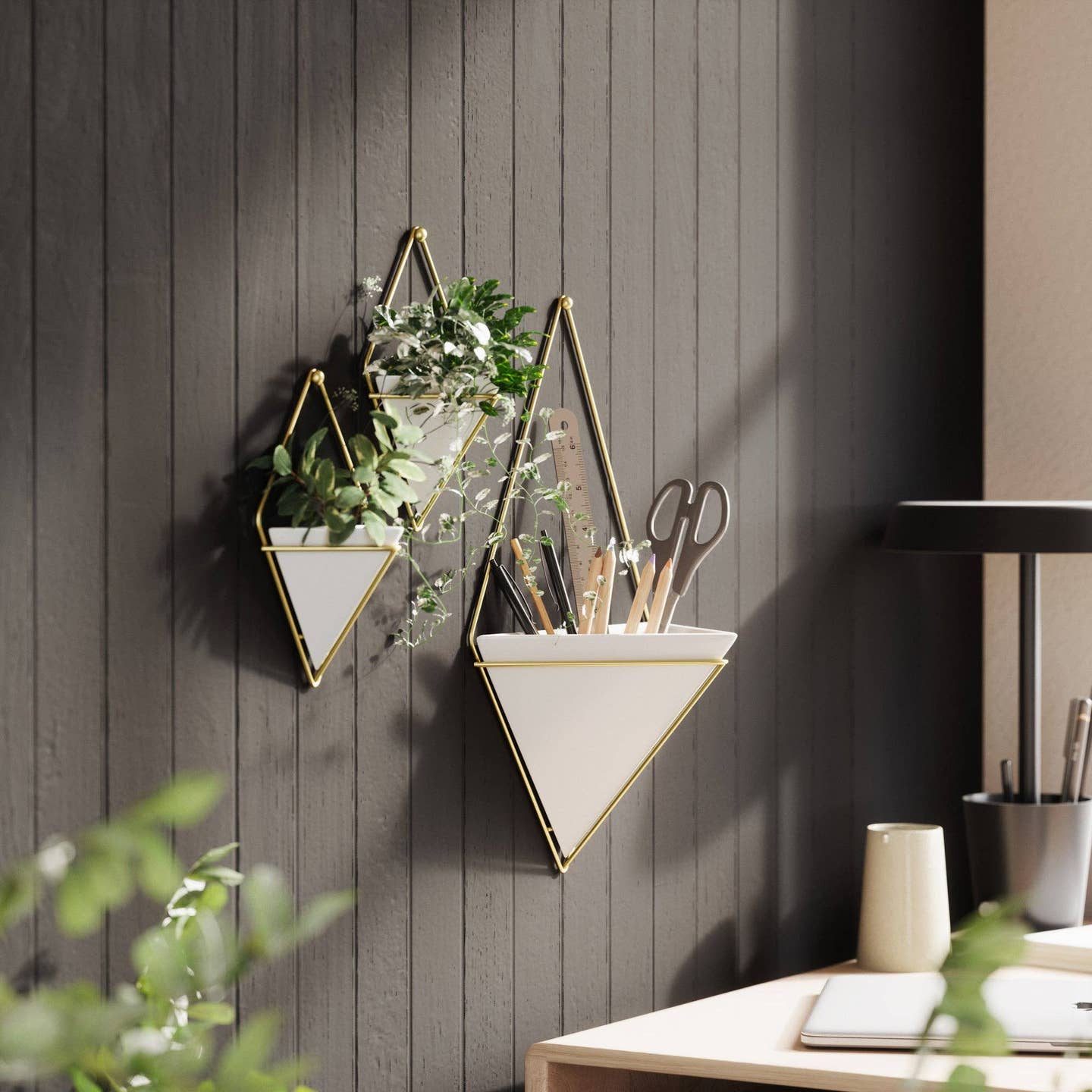 three white triangle shaped wall hanging planters against a black wall