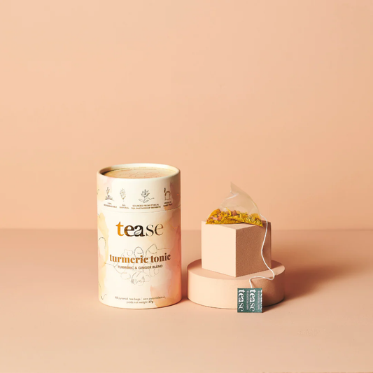 a tin of tease branded turmeric tonic tea next to a tea bag against a peach coloured background