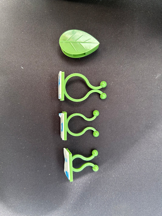 green plastic clips with one in the shape of a leaf resting on a black surface
