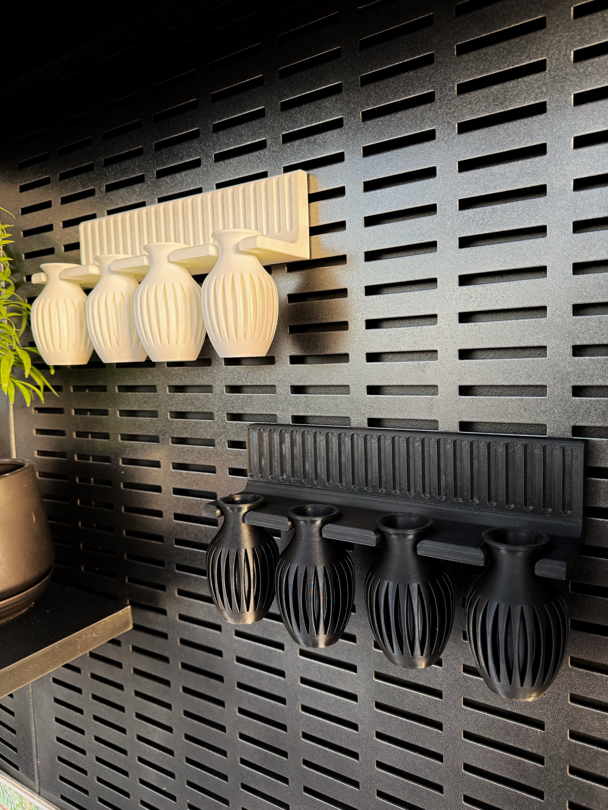A wall mount propagation station with clear test tubes for plant cuttings, mounted on a dark grid wall. The station is made from recycled plastic and is designed to be used for growing plants indoors.