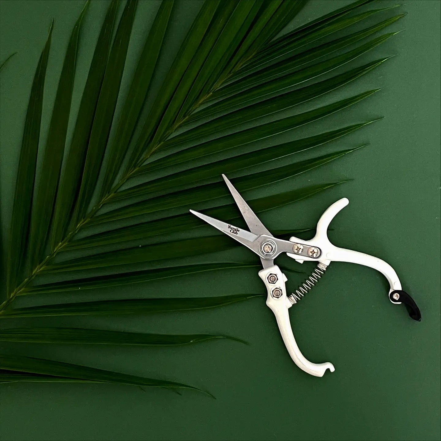 an open pair of white printing shears on a green background