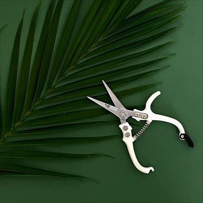 an open pair of white printing shears on a green background