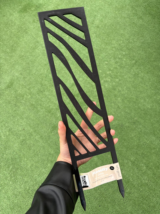 Hand holding a zebra wooden trellis against a green background