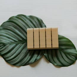 wooden slat block to hold soap against green leaf and white background